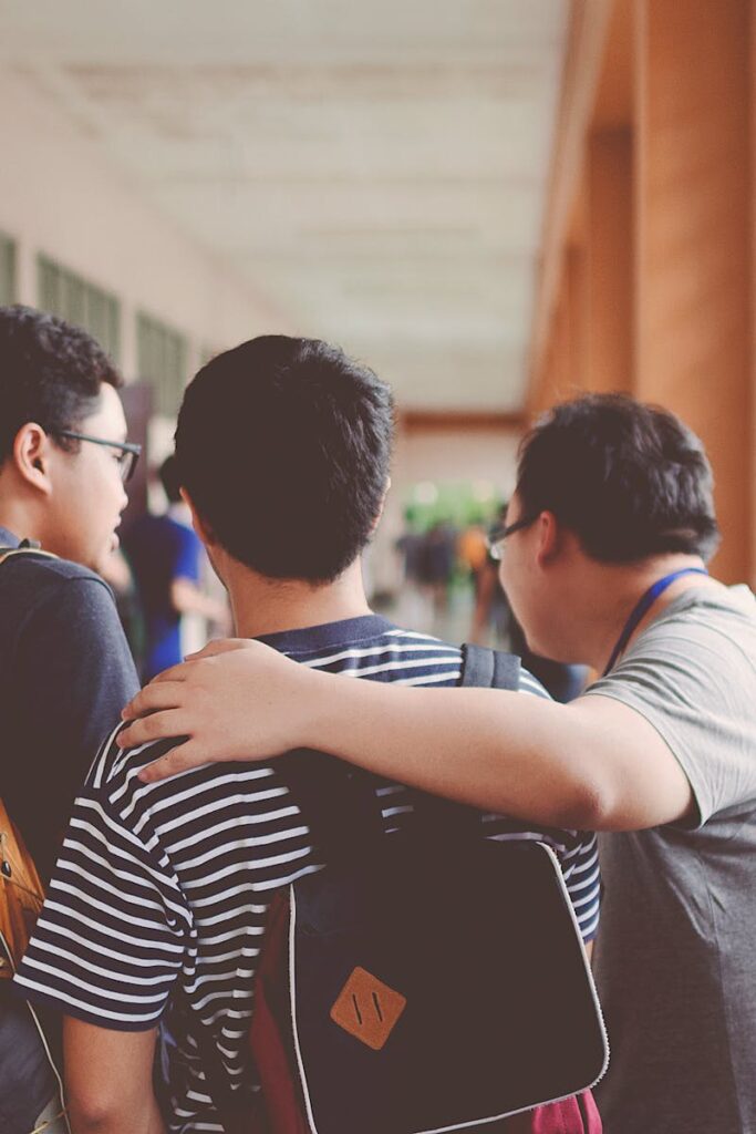 Group of male teenagers walking in a school corridor with backpacks, bonding and chatting.